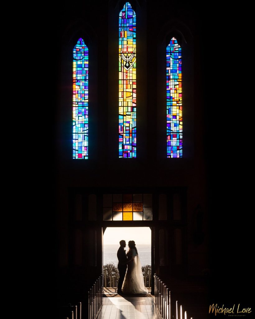 Silhouette of wedding couple underneath church stained glass window