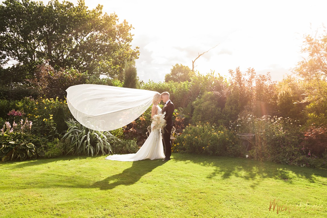 Wedding couple kissing in the sun with veil blowing
