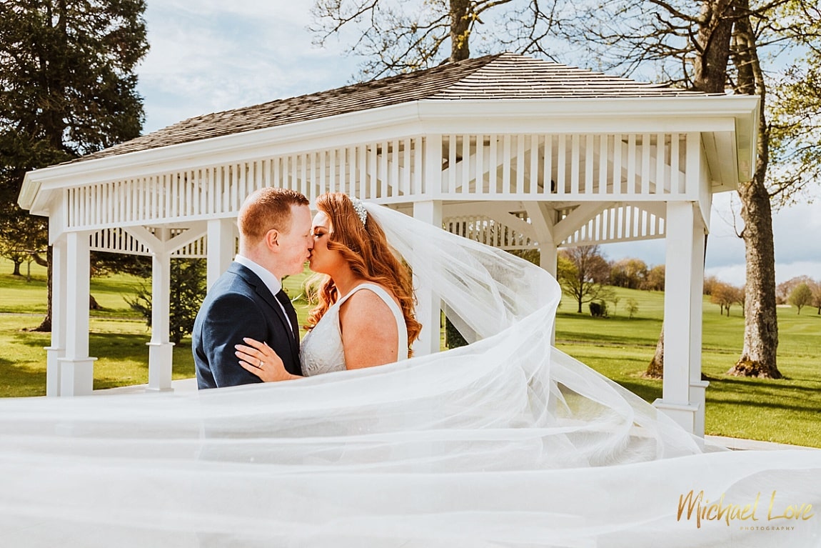 Couple kissing with the bride's veil blowing in wind
