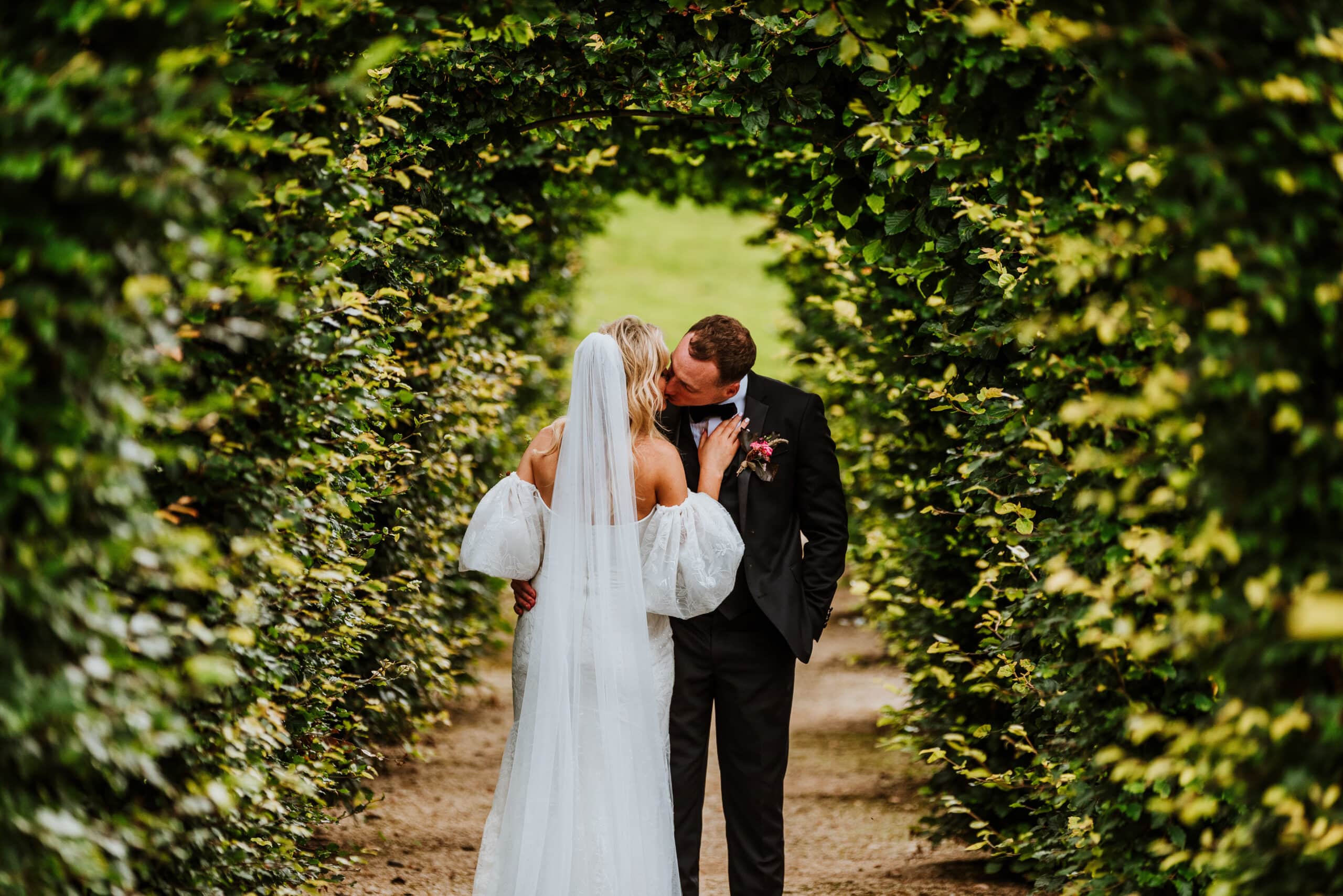 Wedding couple kissing under the arched hedges at Rockhill House, Letterkenny