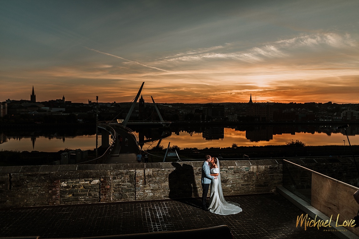 Wedding couple posing in front of the Peace Bridge Derry at sunset